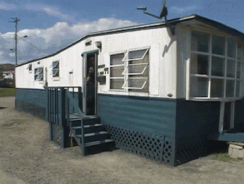 A Blue And White Mobile Home With Stairs Leading Up To The Door GIF