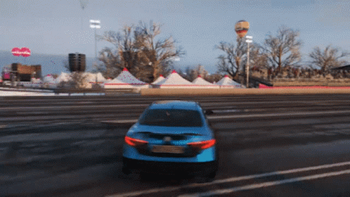 A Blue Car Is Driving Down A Road In Front Of A Sign That Says Nickelodeon GIF