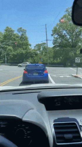 A Blue Car Is Driving Down A Street With A Sign That Says Y On It GIF