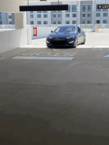A Blue Car Is Parked In A Parking Garage With A Stop Sign GIF