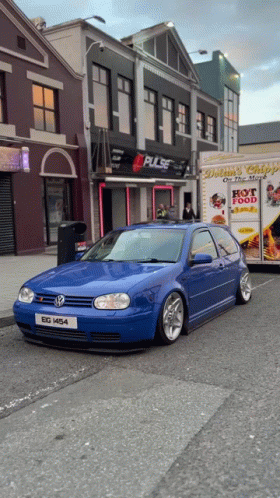 A Blue Car Is Parked In Front Of A Building That Says Pulse On It GIF