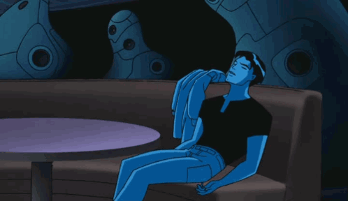 A Blue Cartoon Character Is Sitting On A Couch With A Table In The Background GIF