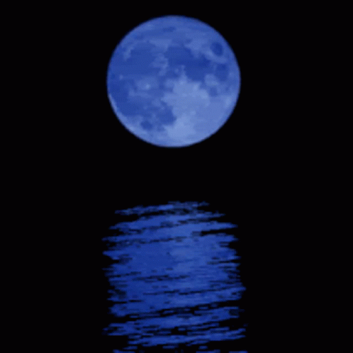 a blue full moon is reflected in a body of water