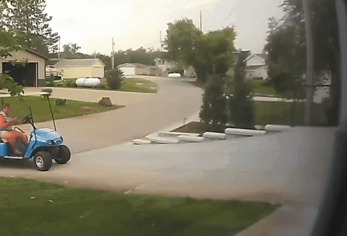 A Blue Golf Cart Is Parked In A Driveway GIF