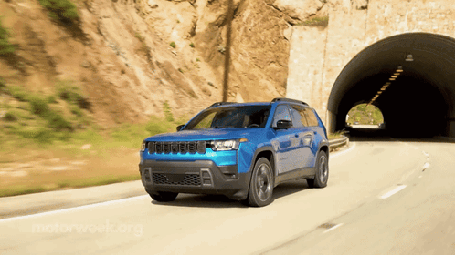 A Blue Jeep Drives Through A Tunnel On A Road GIF