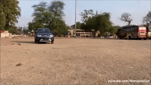 A Blue Jeep Is Driving Down A Dirt Road In Front Of A Bus GIF