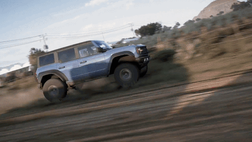 A Blue Jeep Is Driving Through A Dirt Field GIF