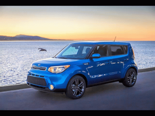 A Blue Kia Soul Is Parked On The Side Of A Road Near The Ocean GIF