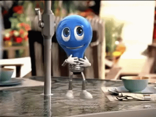A Blue Light Bulb With Arms And Legs Is Standing On A Table Under An Umbrella GIF