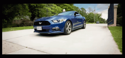 a blue mustang is driving down a road with a license plate that says ' tcj ' on it
