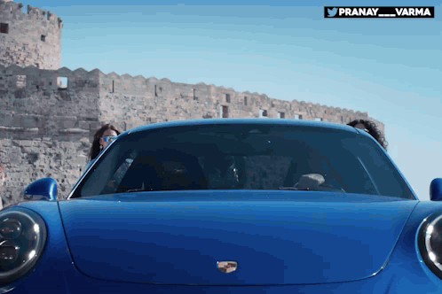 A Blue Porsche Car Is Parked In Front Of A Castle GIF