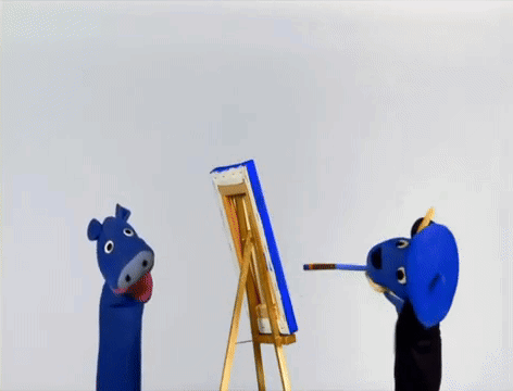 A Blue Puppet Is Painting A Picture On An Easel GIF