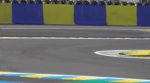 A Blue Race Car Is Going Around A Curve On A Race Track GIF