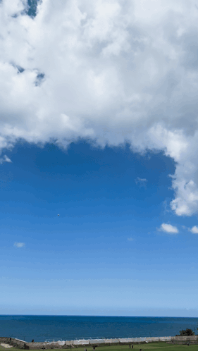 A Blue Sky With White Clouds Over The Ocean And A Golf Course In The Foreground GIF