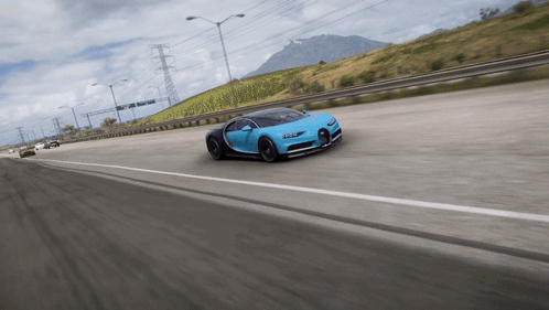 A Blue Sports Car Is Driving Down A Highway With A Mountain In The Background GIF