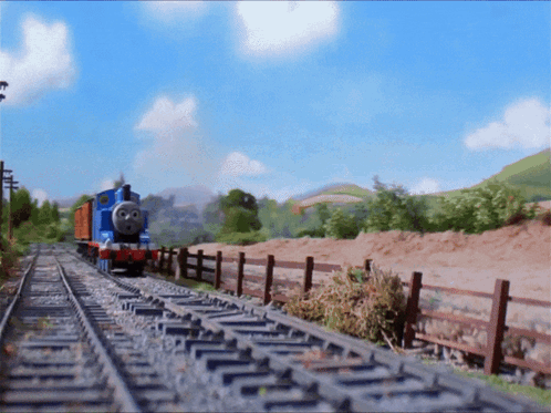 A Blue Train Is Going Down The Tracks In The Countryside GIF