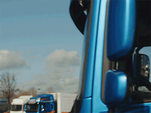 A Blue Truck Is Parked In Front Of A White Truck GIF
