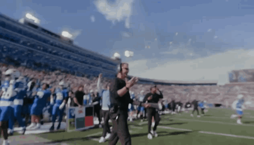 a blurred image of a football field with a man wearing headphones and the number 24 on his shirt