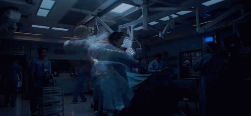 A Blurred Image Of A Hospital Operating Room With A Monitor That Shows The Time As 9:39 GIF