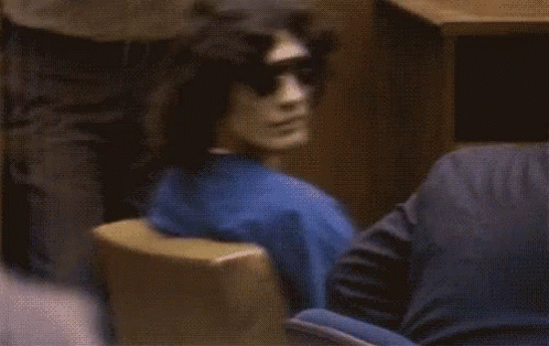A Blurred Image Of A Man Wearing Sunglasses Sitting In A Chair GIF