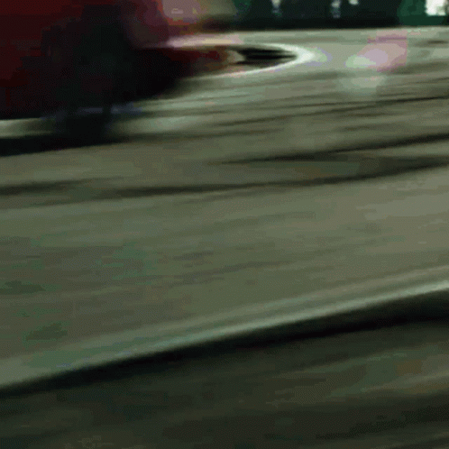 A Blurred Image Of A Red Car Driving Down A Road GIF