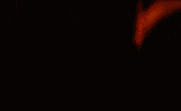 A Blurred Image Of A Red Yellow And Green Cube On A Black Background GIF