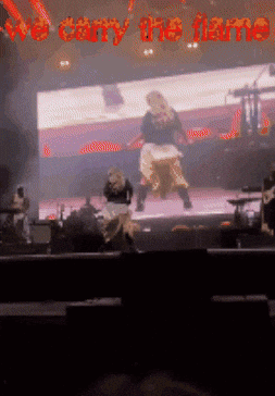 A Blurred Image Of A Stage With The Words We Carry The Flame GIF