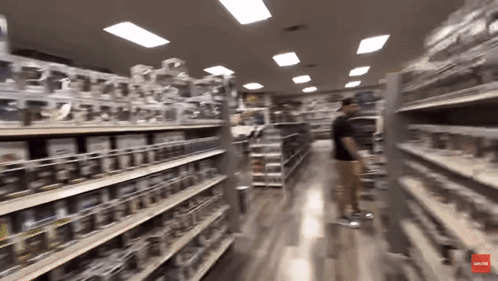 A Blurred Image Of A Store Aisle With A Red Arrow Pointing To The Bottom Left GIF