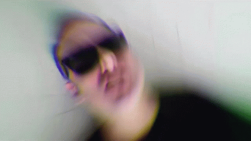 A Blurry Image Of A Person Wearing Sunglasses GIF