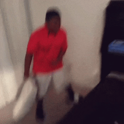 A Blurry Photo Of A Man In A Red Shirt Holding A Pillow GIF
