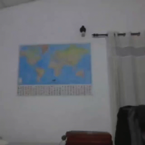 A Blurry Photo Of A Man Standing In Front Of A Map Of The World GIF