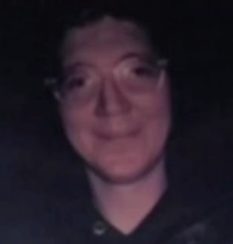 A Blurry Photo Of A Man Wearing Glasses And A Black Shirt GIF