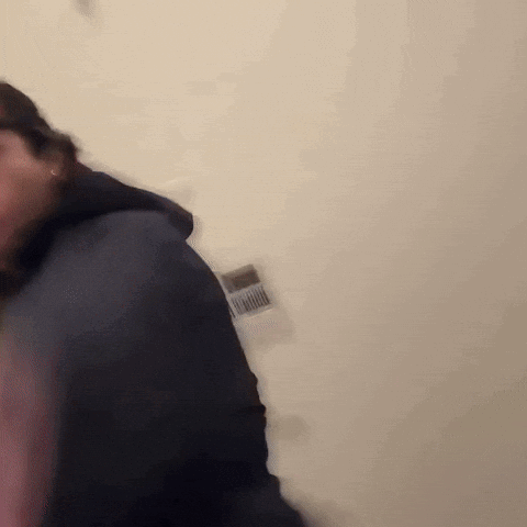 A Blurry Photo Of A Person Standing In Front Of A White Wall GIF