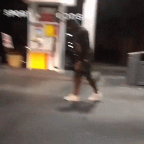A Blurry Photo Of A Person Walking In Front Of A Store That Says Sports GIF