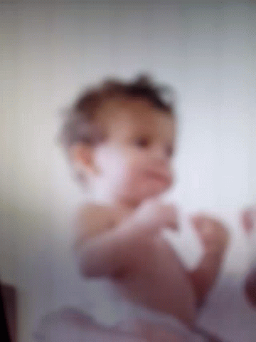 A Blurry Picture Of A Baby Laying On Its Stomach GIF