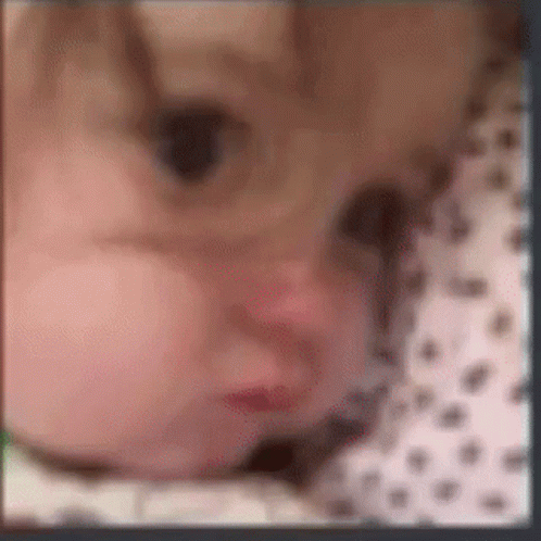 A Blurry Picture Of A Baby 'S Face With A Polka Dot Shirt . GIF