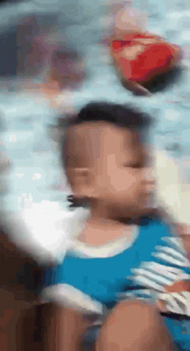 A Blurry Picture Of A Baby With A Blue Shirt On GIF