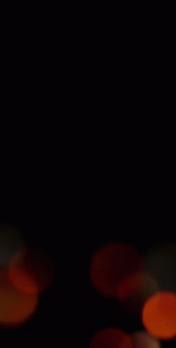 a blurry picture of a bunch of orange circles on a black background .