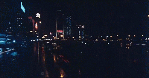 A Blurry Picture Of A City Street At Night With A Sign That Says ' No Smoking ' GIF