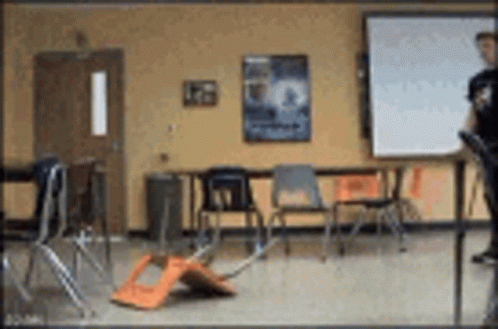 A Blurry Picture Of A Classroom With Chairs And Tables GIF