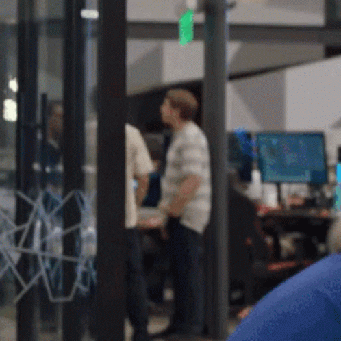 A Blurry Picture Of A Group Of People In A Room With Computers GIF