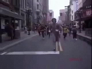 A Blurry Picture Of A Group Of People Running Down A Street . GIF