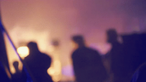 A Blurry Picture Of A Group Of People Standing In Front Of A Stage GIF