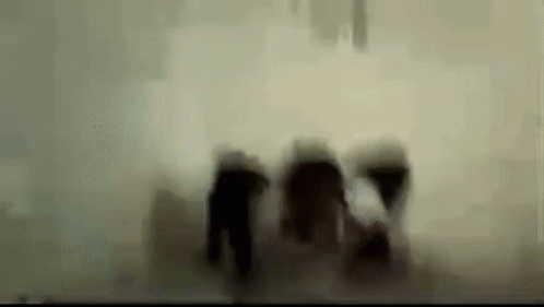 A Blurry Picture Of A Group Of People Walking In The Dark . GIF