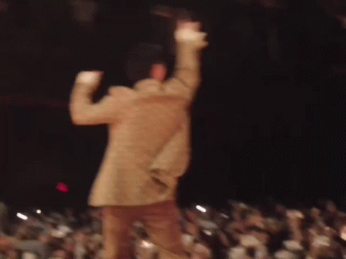 A Blurry Picture Of A Man Dancing On Stage In Front Of A Crowd . GIF
