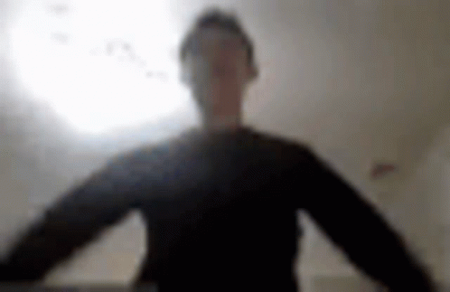 A Blurry Picture Of A Man In A Black Shirt Standing In Front Of A Light . GIF