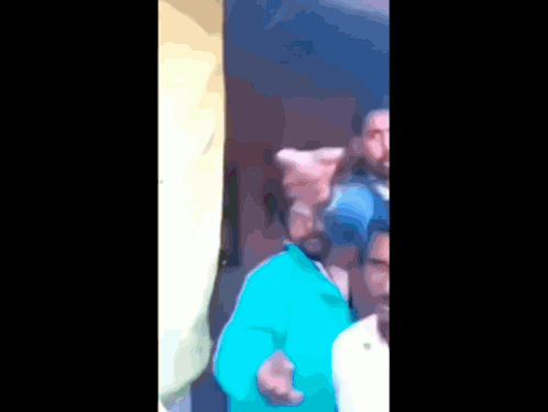 A Blurry Picture Of A Man In A Blue Shirt Pointing At Something GIF
