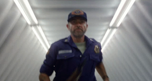 A Blurry Picture Of A Man In A Blue Uniform With A Badge That Says ' Emergency ' On It GIF