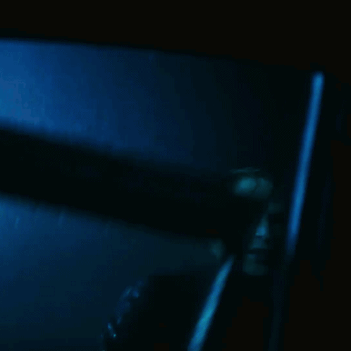 A Blurry Picture Of A Man In A Dark Room With A Blue Background GIF