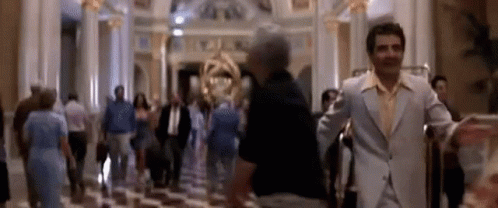 A Blurry Picture Of A Man In A Suit Standing In A Lobby Of A Hotel . GIF